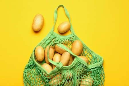 String bag with raw potatoes on color backgroundの写真素材
