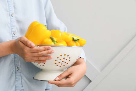 Woman holding colander with yellow bell pepper, closeupの写真素材