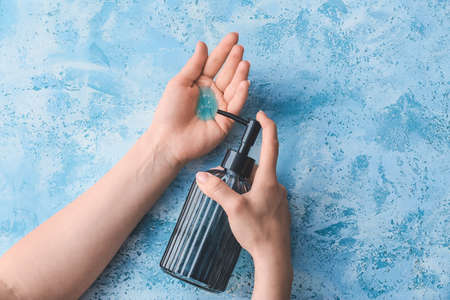 Young woman washing her hands on color backgroundの写真素材