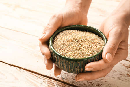 Female hands with healthy quinoa in bowl on wooden backgroundの写真素材