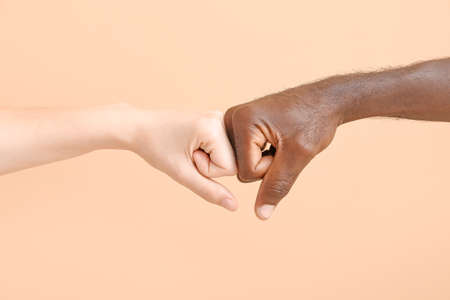 Caucasian woman and African-American man bumping fists on color background. Racism conceptの写真素材