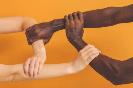 Caucasian woman and African-American man holding hands together on color background. Racism conceptの写真素材