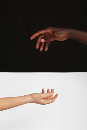 Hands of Caucasian woman and African-American man on black and white background. Racism conceptの写真素材