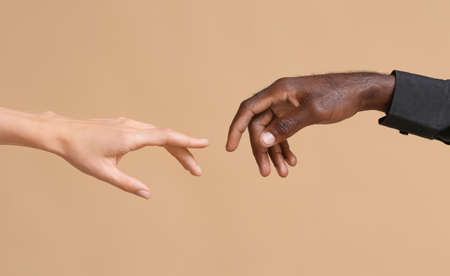 Hands of Caucasian woman and African-American man reaching out to each other on color background. Racism conceptの写真素材