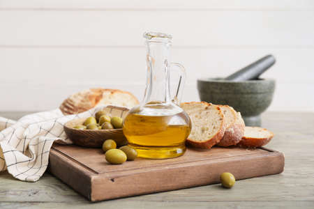 Bottle of tasty olive oil and bread on tableの写真素材