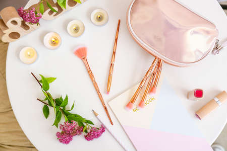 Makeup bag with decorative cosmetics and flower on dressing table