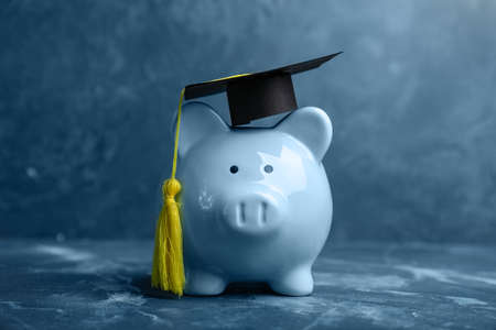 Piggy bank with graduation hat on table. Tuition fees conceptの写真素材
