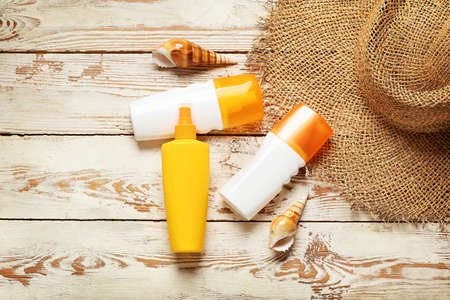Beach accessories with sunscreen cream on white wooden background
