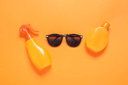 Bottles of sunscreen with sunglasses on color backgroundの写真素材