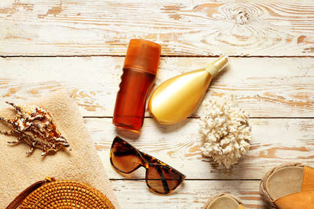 Beach accessories with sunscreen cream on white wooden background