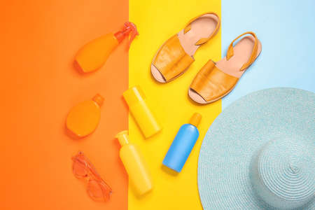 Beach accessories with sunscreen cream on color background