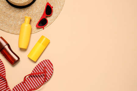 Beach accessories with sunscreen cream on color background