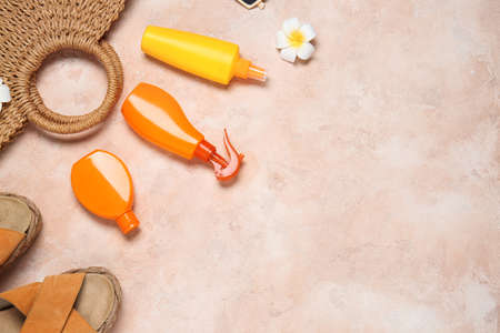 Beach accessories with sunscreen cream on color background