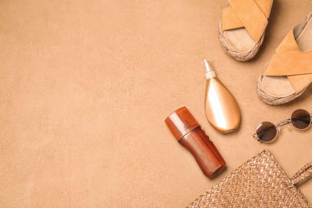 Beach accessories with sunscreen cream on color background