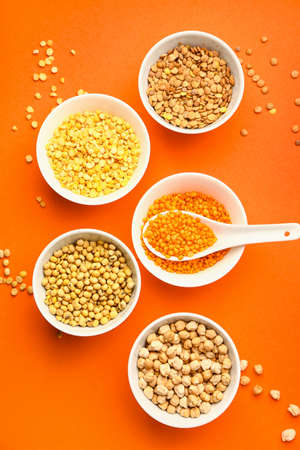 Different raw legumes on color background
