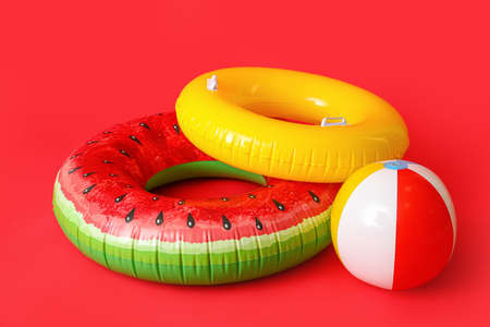 Inflatable rings and ball on color background
