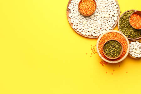 Different raw legumes on color background