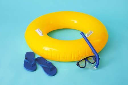 Inflatable ring, snorkeling mask and flip-flops on color backgroundの写真素材
