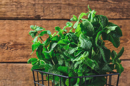 Fresh green mint in basket on wooden backgroundの写真素材