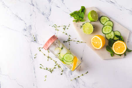 Bottle of herbal infused water with cucumber and citrus on light tableの写真素材