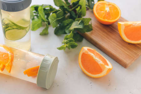 Bottles of mint infused water with orange on light tableの写真素材