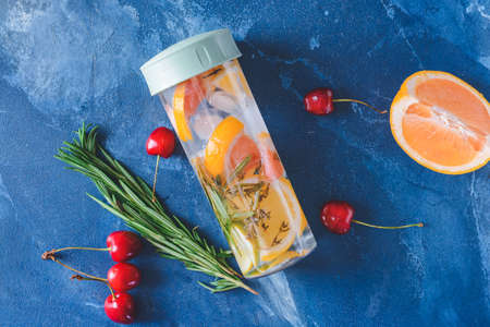 Bottle of herbal infused water with citruses on color tableの写真素材