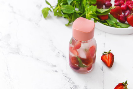 Bottle of mint infused water with berries on light tableの写真素材
