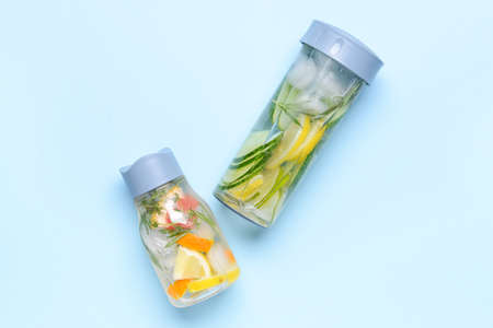 Bottles of infused water with citruses and cucumber on color backgroundの写真素材