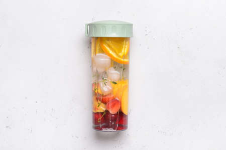 Bottle of infused water with citruses and berries on light backgroundの写真素材