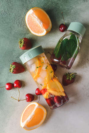 Bottles of infused water with berries and citrus on color backgroundの写真素材