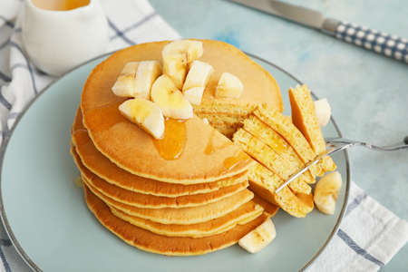 Plate with tasty banana pancakes on table