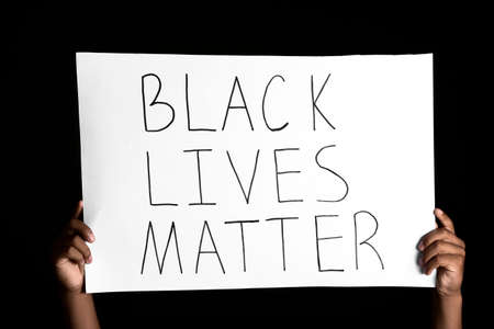 African-American teenage boy with poster on dark background. Stop racismの写真素材