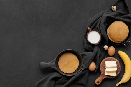 Tasty banana pancakes with ingredients on dark backgroundの写真素材