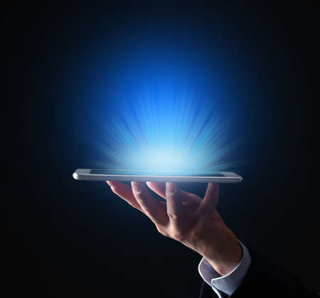 Businessman with tablet computer on dark backgroundの写真素材