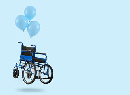 Flying wheelchair with air balloons on color backgroundの写真素材