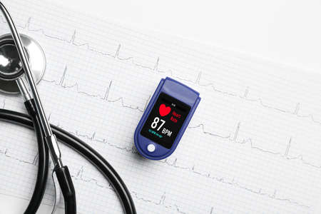 Pulse oximeter, stethoscope and cardiogram on white background