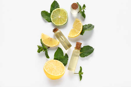 Essential oil, mint and citrus fruits on white background