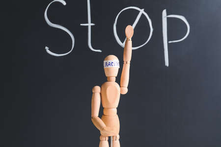 Mannequin with word RACISM on head near chalkboard with word STOPの写真素材