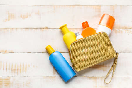 Bag with sunscreen cream on white wooden background