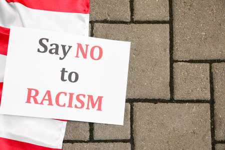 Paper with text SAY NO TO RACISM and flag of USA outdoorsの写真素材