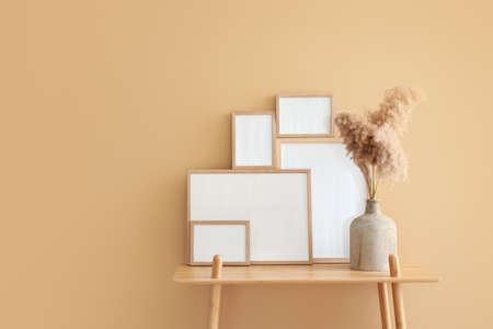 Table with blank frames and vase near color wall