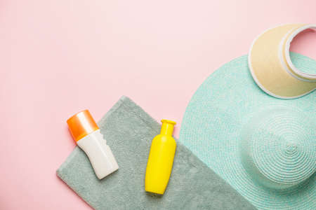 Beach accessories with sunscreen cream on color background