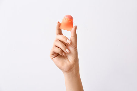 Female hand with natural lip balm on light backgroundの写真素材