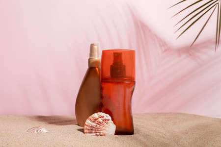 Bottles of sunscreen cream on sand against color backgroundの写真素材