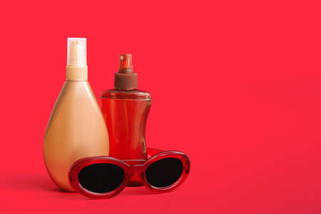 Bottles of sunscreen with sunglasses on color backgroundの写真素材