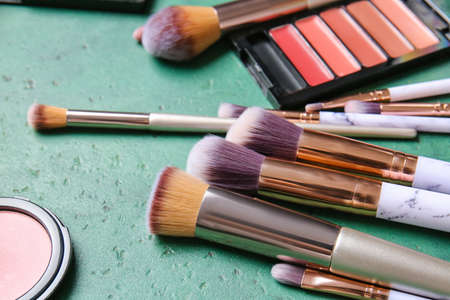 Set of makeup brushes and cosmetics on color background, closeup