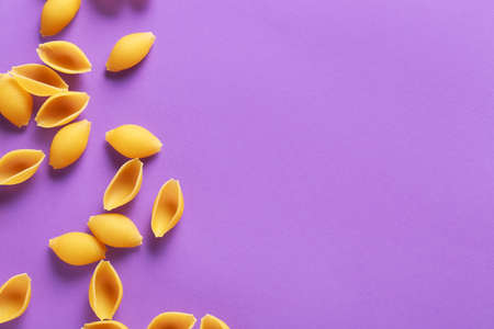 Dry conchiglie pasta on color background