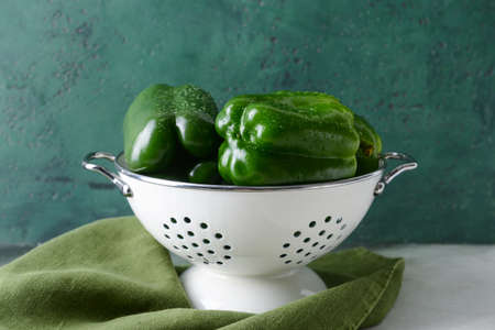 Green bell pepper in colander on table