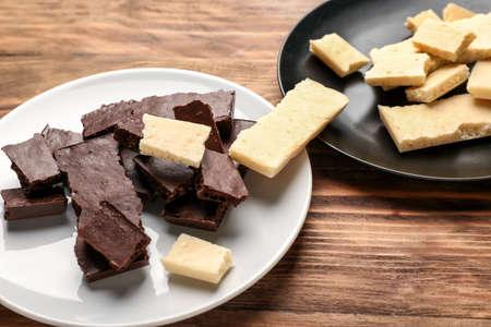 Plates with different chocolate on wooden background. Racism concept