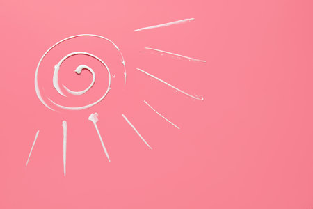 Sun drawn with sunscreen cream on color backgroundの写真素材